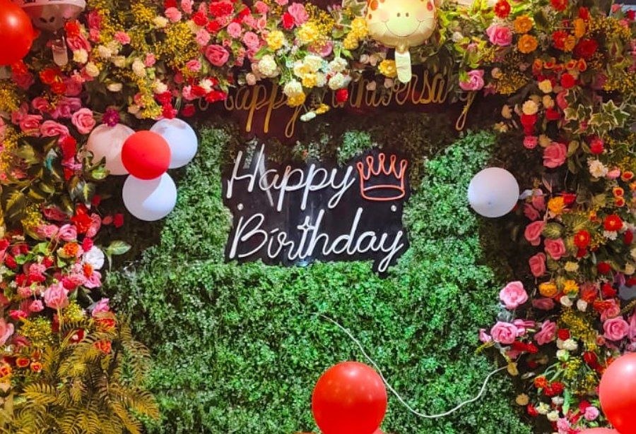 Floral photo wall with Happy Birthday neon sign